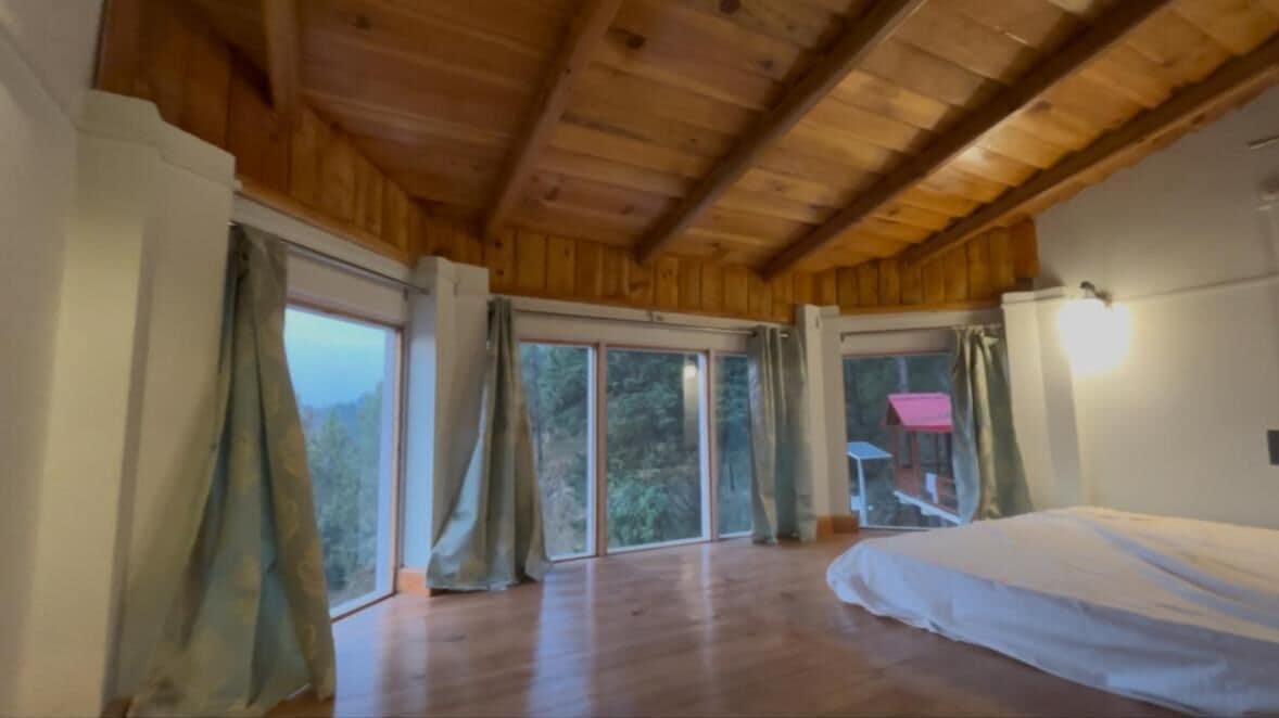 A room with wooden ceiling beams, large sliding glass doors, and a bed.