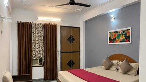 Une chambre à coucher avec un lit, des rideaux, un tableau et un ventilateur de plafond.