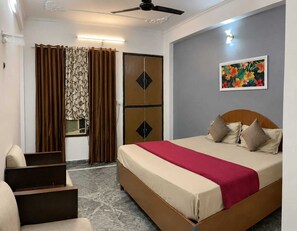 A bedroom with a bed, curtains, a painting, and a ceiling fan. - nancy paradise hotel (Roorkee)