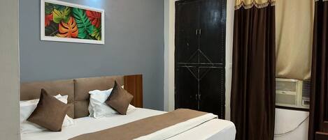 A neatly made bed with a headboard, a wall-mounted light fixture, and a window with curtains.
