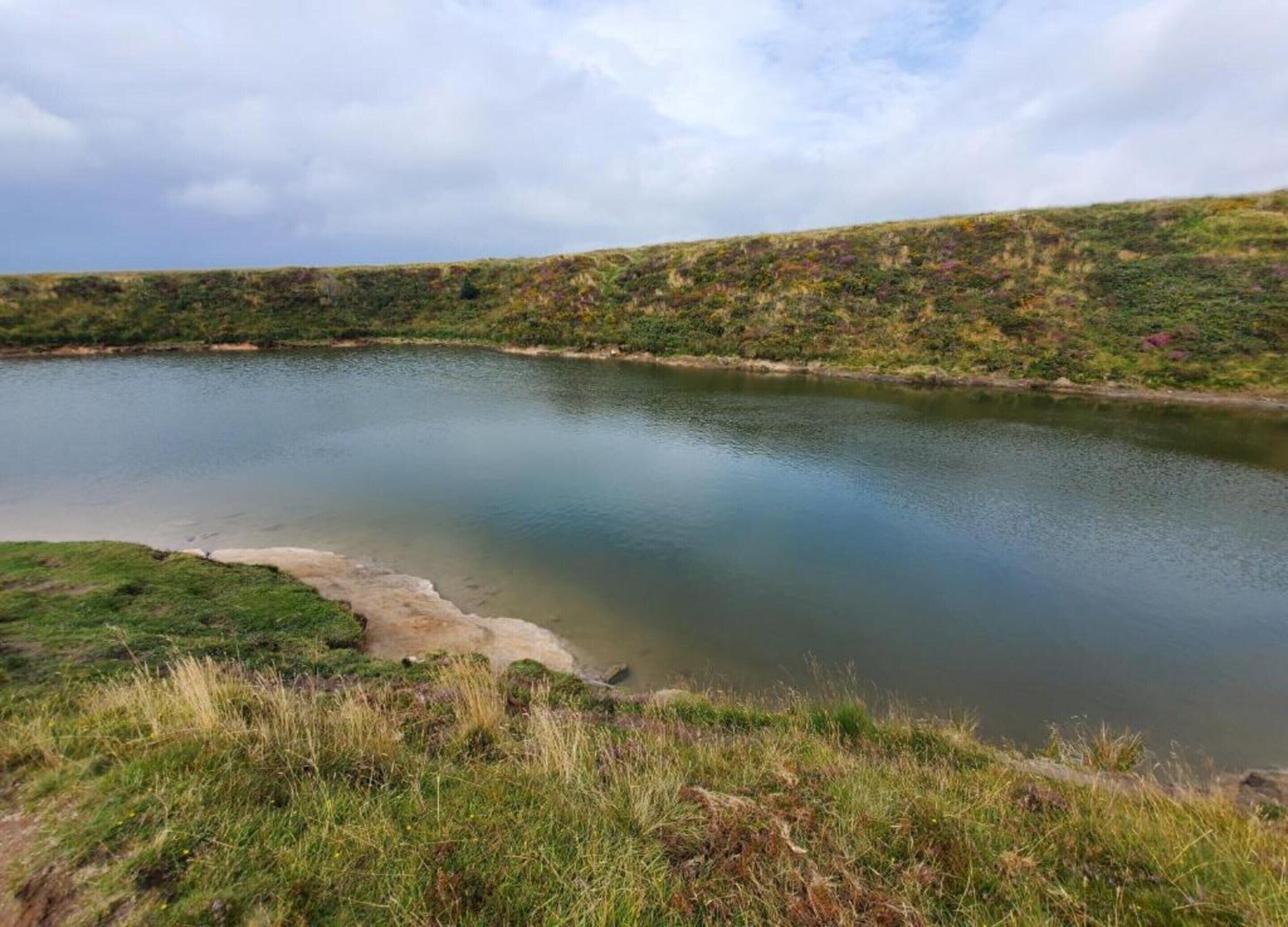 A calm lake surrounded by grassy terrain.