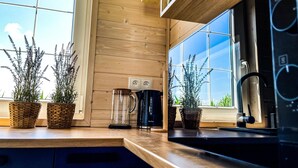 A kitchen with wooden cabinets, a coffee maker, and potted plants. - Cottage Near Kopan Beach and Lake (Darlowo)