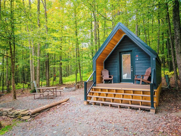 A cabin with a porch, a door, and two chairs. - A-frame Principal (Wellsboro)