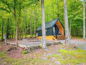 A cabin with a wooden deck, a bench, and a stone wall. - A-frame Principal (Wellsboro)