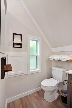 A bathroom with a white toilet, a window, and a towel rack. - A-frame Principal (Wellsboro)