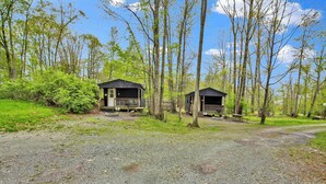 A campground with two cabins, gravel paths, and surrounding trees. - Cabin full bath (Wellsboro)