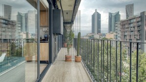 A modern balcony with a city view, a glass door, and potted plants. - Myla Chapultepec (Mexico City)