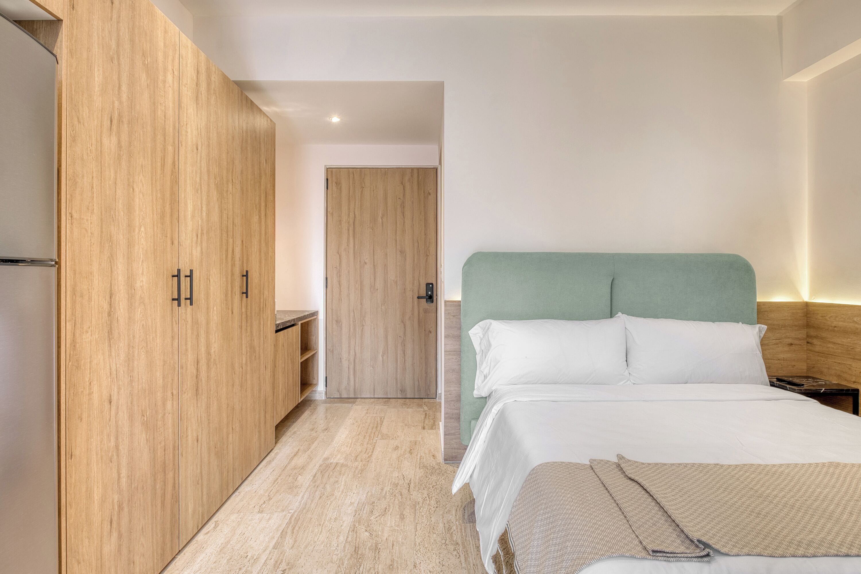 Una habitación de hotel moderna con una cama, un armario y una pequeña zona de estar.