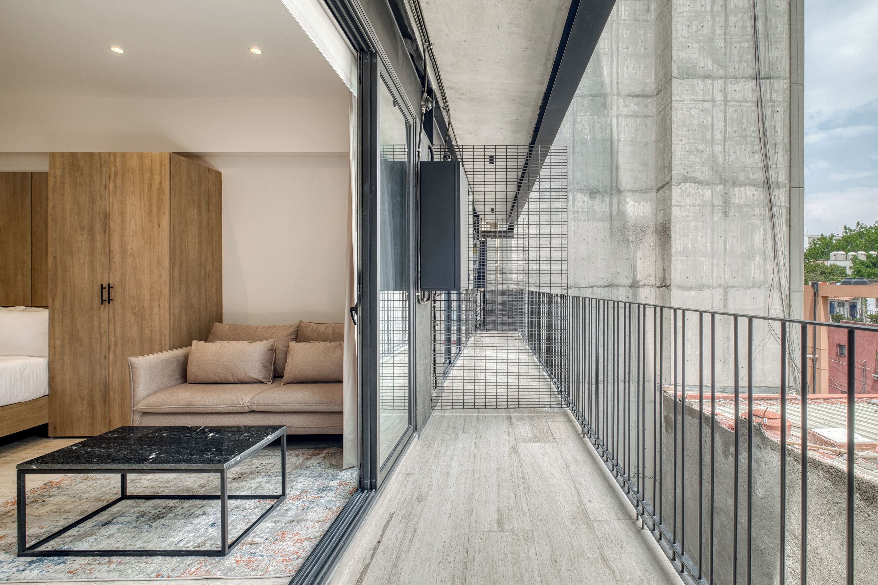 A modern apartment with a balcony, a sofa, a bed, and a coffee table.