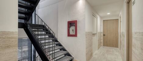 A modern interior with a staircase, a framed picture, and a wooden door.