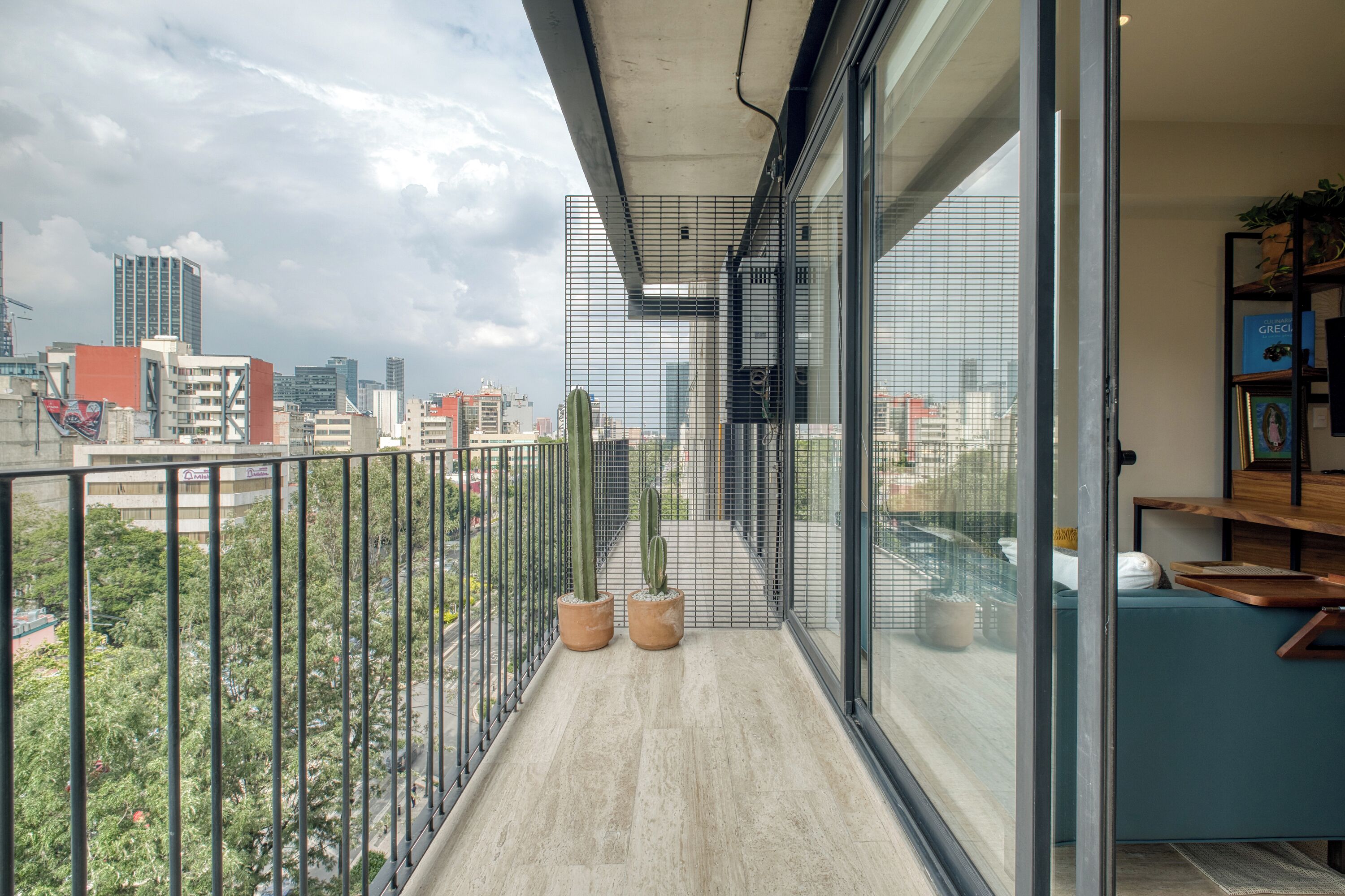 Uma varanda com vista para a cidade, porta de vidro e um espaço de estar com uma planta.