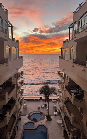 A hotel with a pool and outdoor seating, overlooking a beach at sunset. - Sun, Sand, & Sea: Mazatlán Condo (Mazatlán)