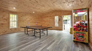 A room with a ping pong table, wooden walls, and a claw machine.