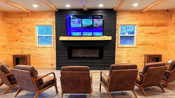 A cozy room with a fireplace, wooden walls, and a TV displaying animal songs and shows. - Tent and Tear Drop Electric site 10 (Wellsboro)
