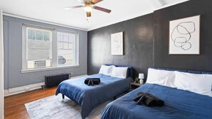 A bedroom with two beds, a ceiling fan, and artwork on the walls. - Bright&inviting~1BR suite~In Uptown (Charlotte)