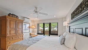 A bedroom with a large bed, wooden wardrobe, ceiling fan, and a view of greenery outside. - Saint James Place 309A (Beaver Creek)