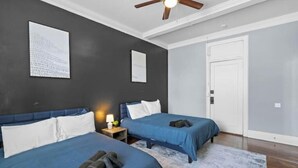 A bedroom with two beds, a ceiling fan, and a white door. - Cozy&Central Suite~1BR~In Uptown (Charlotte)