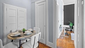 A dining area with a round table set for four, white chairs, and a small plant on the table. - Cozy&Central Suite~1BR~In Uptown (Charlotte)