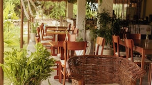 An outdoor patio with wicker furniture, potted plants, and string lights. - Pura Vida Hotel (Itarema)