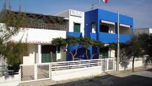 A two-story building with a blue facade, a white balcony, and a flag on top. - Blue Sky Appartamenti San Foca (San Foca)
