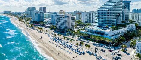 A coastal cityscape with a beach, high-rise buildings, and a clear sky.