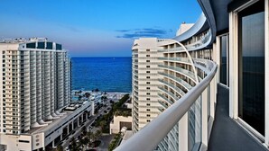 Een hoog hotel met een gebogen balkon met uitzicht op een strand en zee.