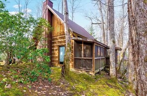 A rustic cabin with a wooden exterior, a large window, and a porch area. - Cozy Cabin w/Creekside Hot Tub (Cosby)