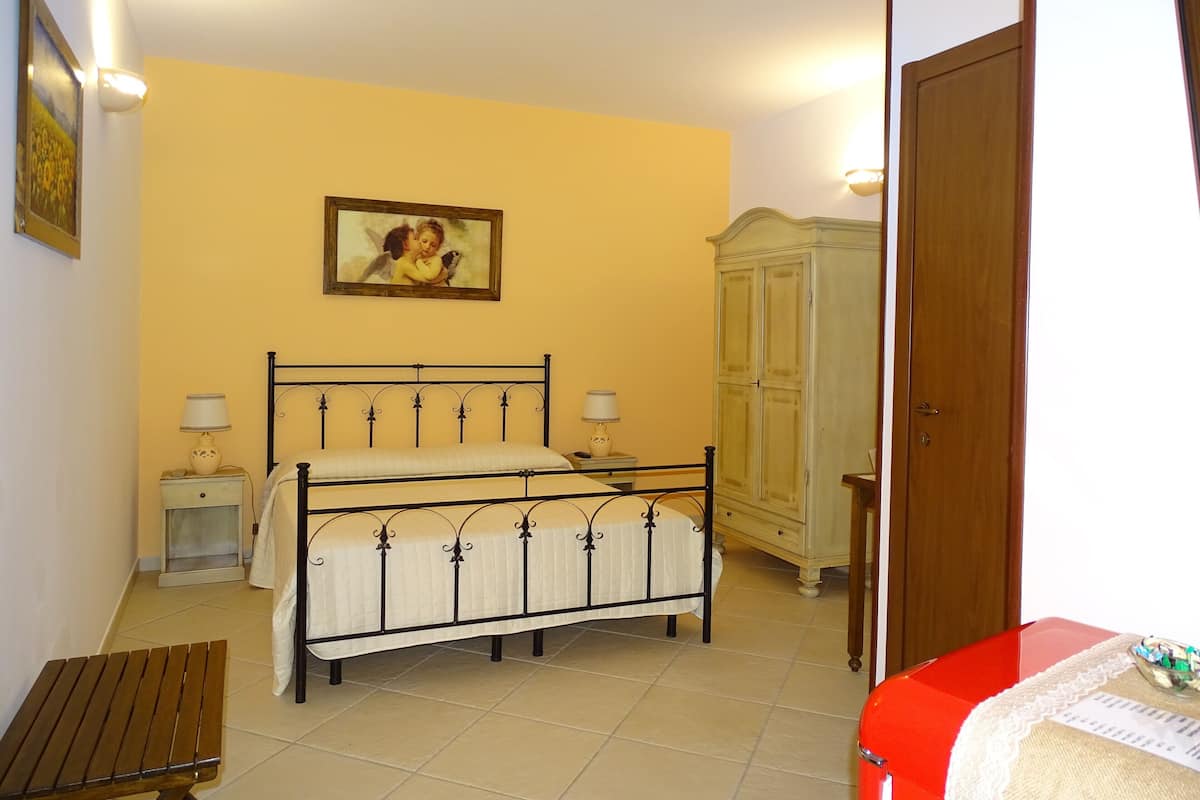 A bedroom with a bed, bedside tables, a wardrobe, and a bench.