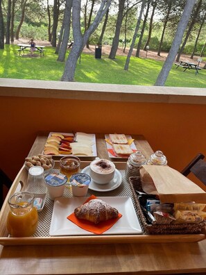 A breakfast tray with various foods and drinks on a table with a view of a park. - Sole del Mediterraneo (Otranto)