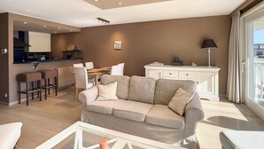 Een moderne woonkamer met een bank, een salontafel en een eethoek met stoelen en een tafel.