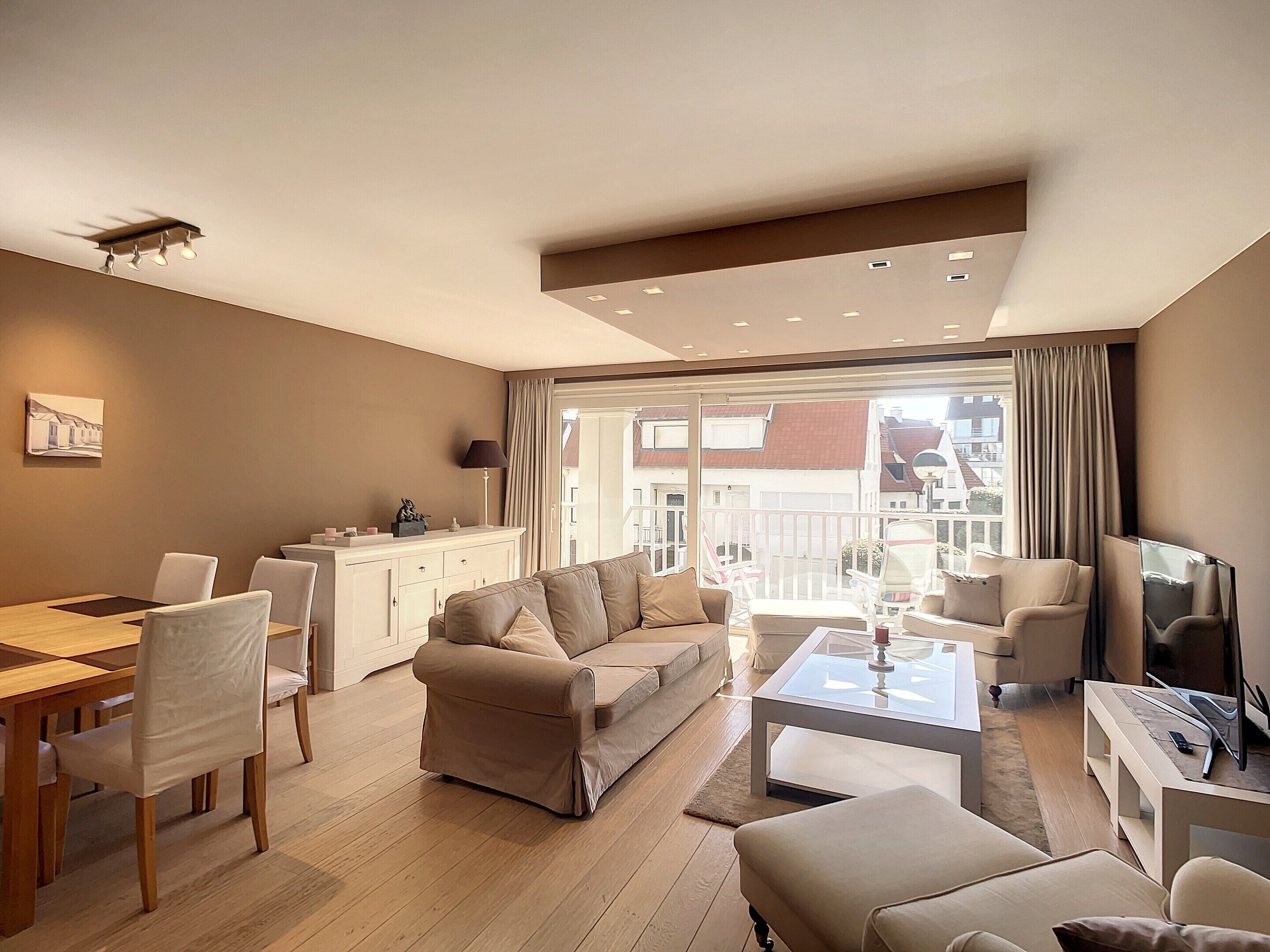 A modern living room with a sofa, chairs, a coffee table, and a dining area with a table and chairs.