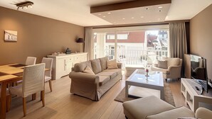 Een moderne woonkamer met een bank, stoelen, een salontafel, en een eethoek met een tafel en stoelen.