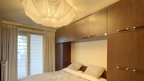 Een slaapkamer met een groot bed, een houten garderobe en een plafondlamp.