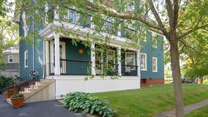 A two-story house with a front porch, a small garden, and a tree in front. - Luxury on Back Cove - Three Gables (Portland)