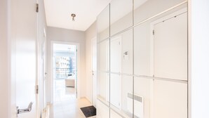 Un couloir au design moderne, doté d’une porte en verre donnant sur un balcon avec vue sur les immeubles.