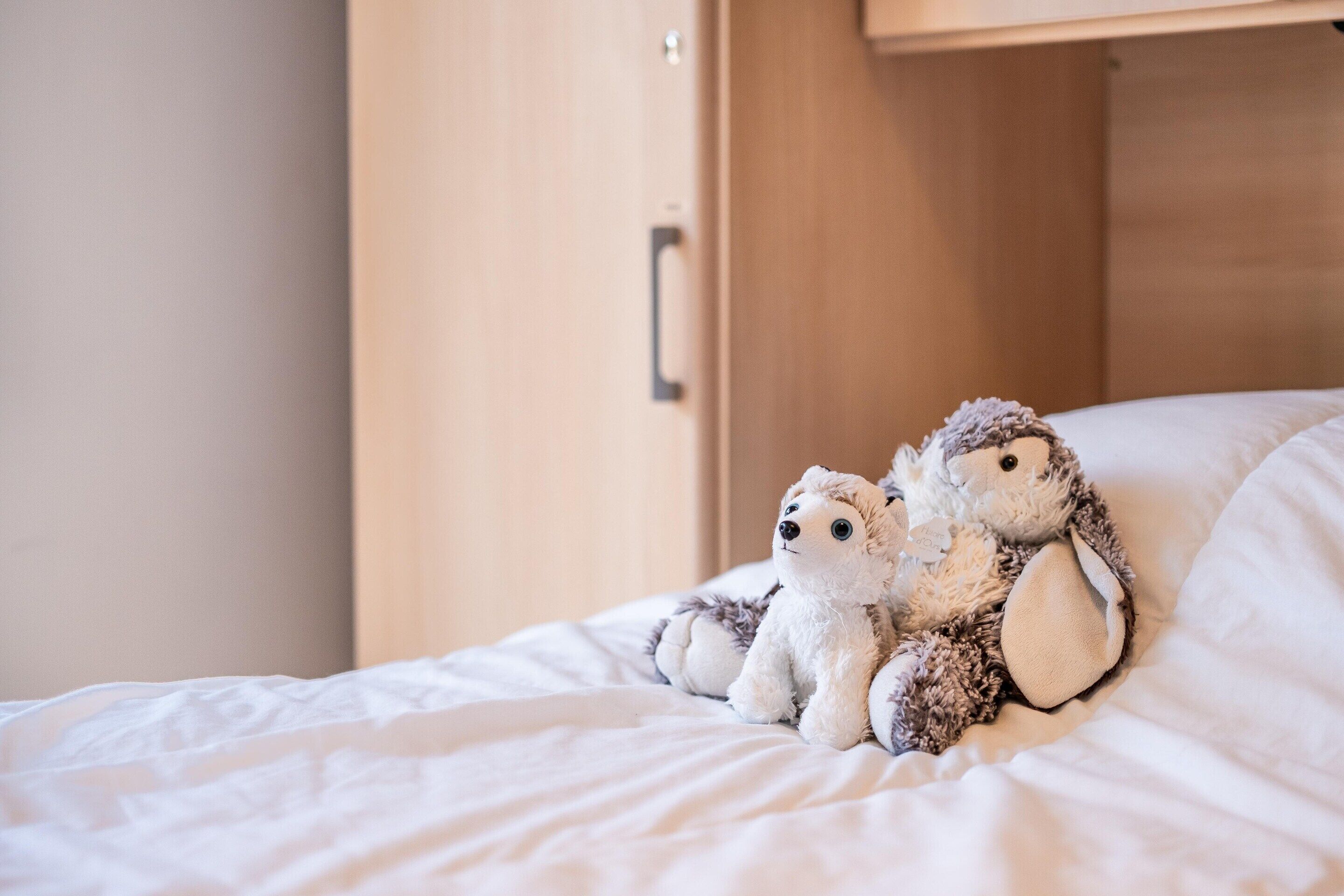 Un lit sur lequel sont posés deux peluches.