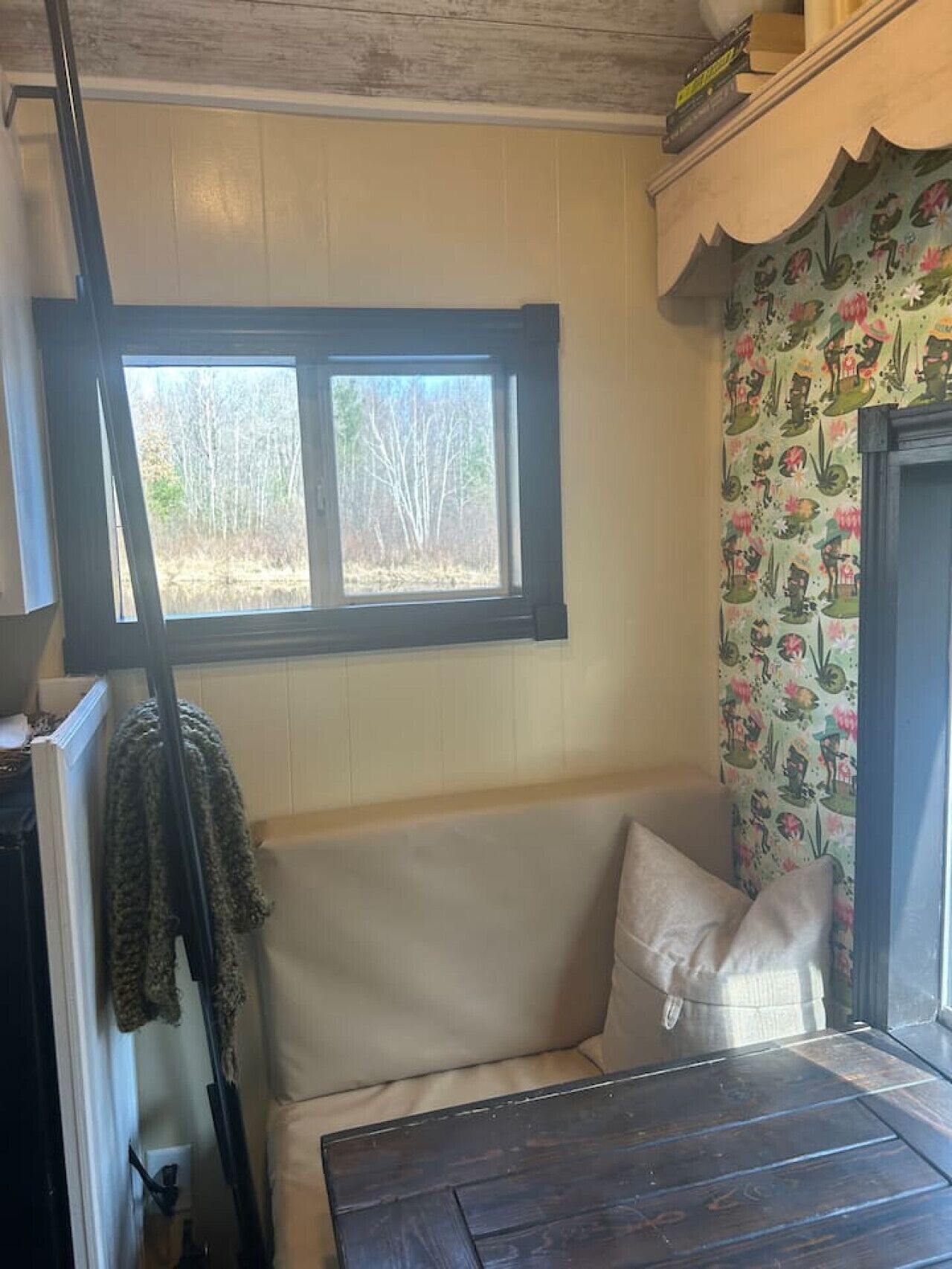 A corner room with a window, a bench, and a patterned wallpaper.
