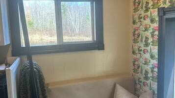 A corner room with a window, a bench, and a patterned wallpaper.