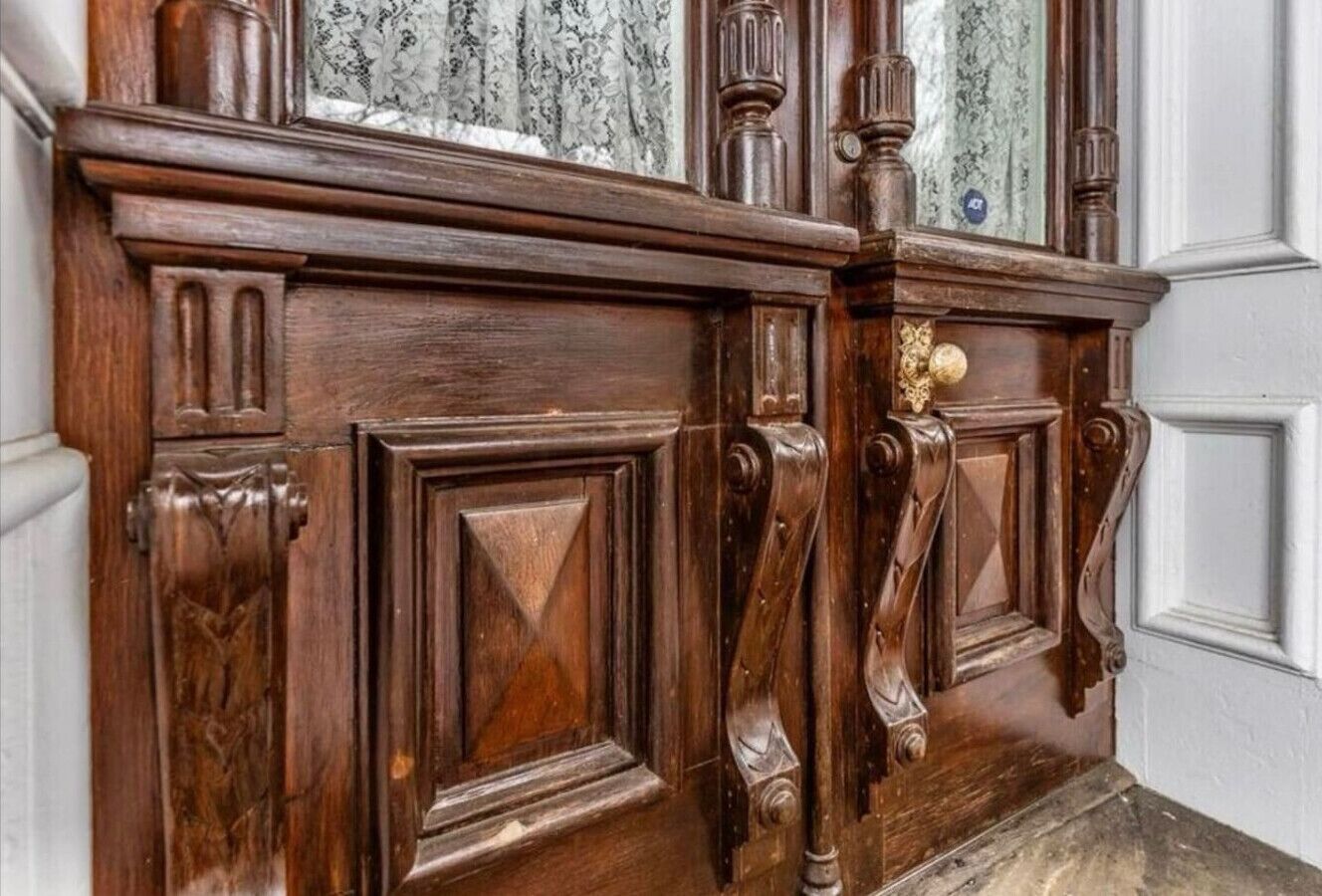 A wooden paneling with intricate carvings and a brass doorknob.