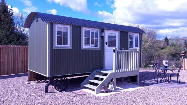 A small, single-story cabin with a porch and a staircase leading to the door. - Cabin for 2 With Walks, Wifi, bat and Restaurant (Forfar)