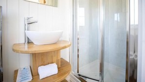 A bathroom with a white sink, wooden vanity, and a glass shower enclosure. - Cabin for 2 With Walks, Wifi, bat and Restaurant (Forfar)