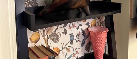 A bookshelf with a decorative bird sculpture, a pink textured vase, and books.