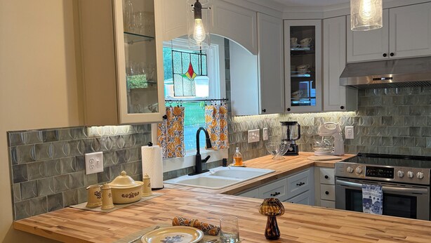 Eine moderne Küche mit einer zentralen Kochinsel, Holzküchenstühlen, einem eingebauten Backofen und einer Spritzschutzleiste mit geometrischen Mustern.