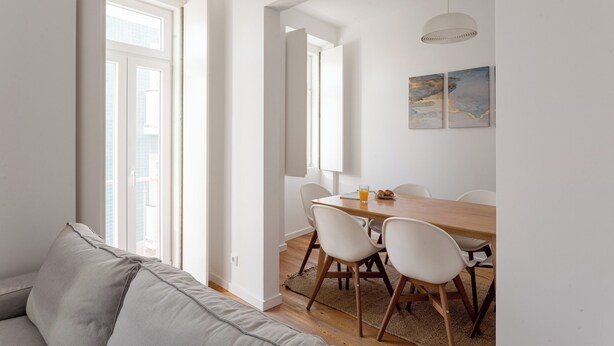 Un espace repas moderne avec une table en bois, des chaises blanches et un luminaire suspendu.