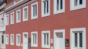 A red building with white windows and doors, a cobblestone street, and a clear blue sky. - The Lisbon Urban Nook Studio (Lisbon)