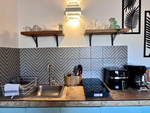 Una cocina moderna con un lavamanos de acero inoxidable, una cafetera y un microondas.
