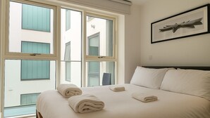 A hotel room with a large bed, multiple windows, and a framed artwork on the wall. - Still Life Farringdon (London)