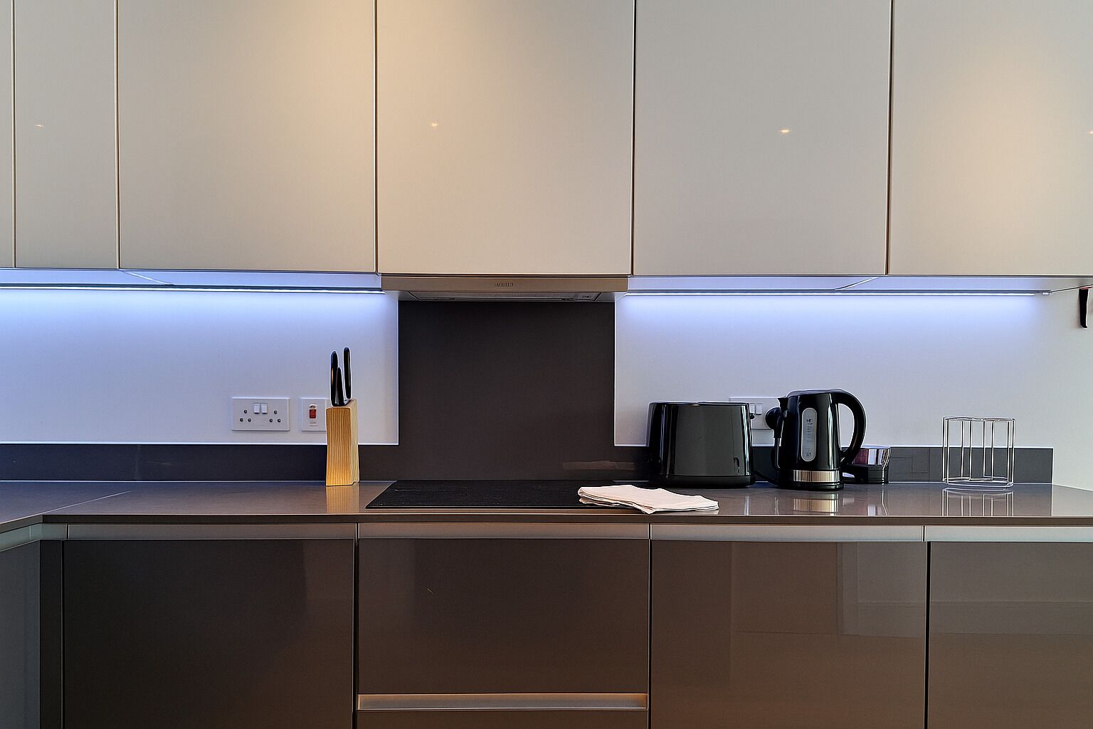 A modern kitchen with stainless steel cabinets, a black countertop, and a built-in range hood.