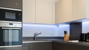 A modern kitchen with a built-in oven, a stainless steel sink, and a wooden floor. - Still Life Farringdon (London)