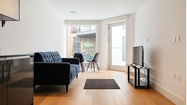 A modern living room with a sofa, TV, and dining area. - Still Life Farringdon (London)